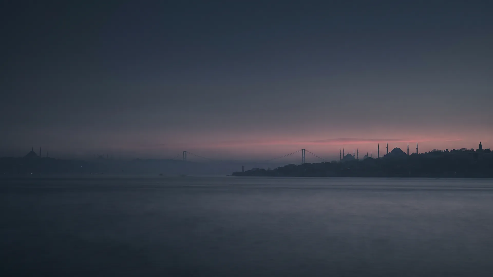İstanbul at dusk, seen across the Bosphorus, with the bridge and the old city in silhouette.