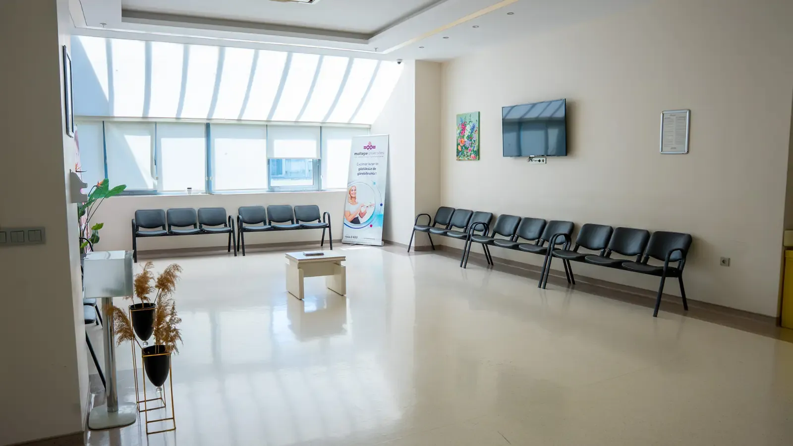 A waiting area with rows of seating under a long skylight window.