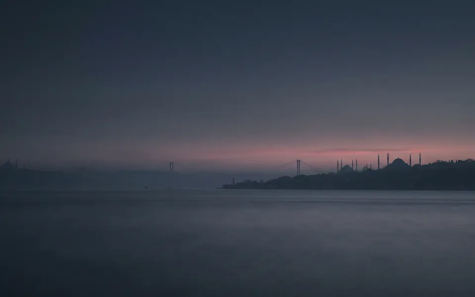 Alacakaranlıkta Boğaz'ın karşı kıyısından görünen İstanbul; köprü ve tarihi yarımada siluet hâlinde.